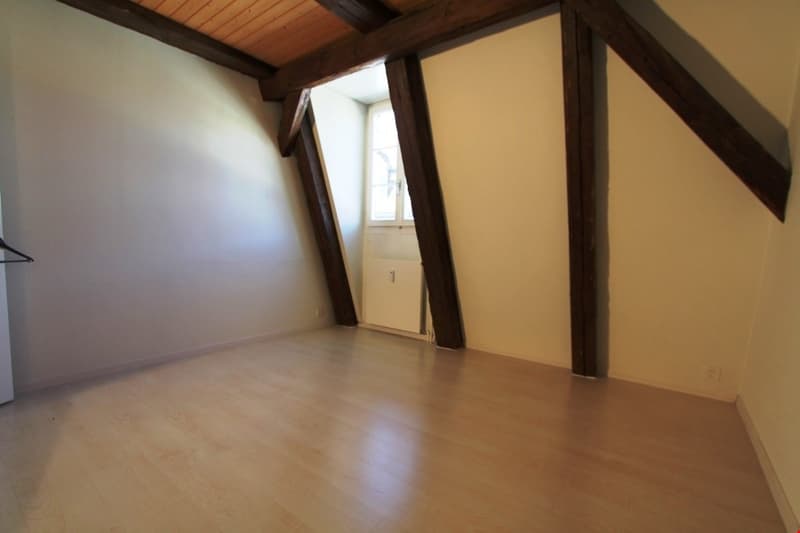 empty room, wooden beams, wooden floor, white walls, small window