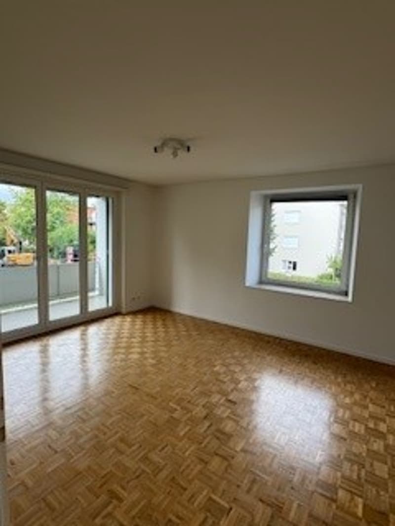 Empty room, wooden floor, two sliding doors, a small window