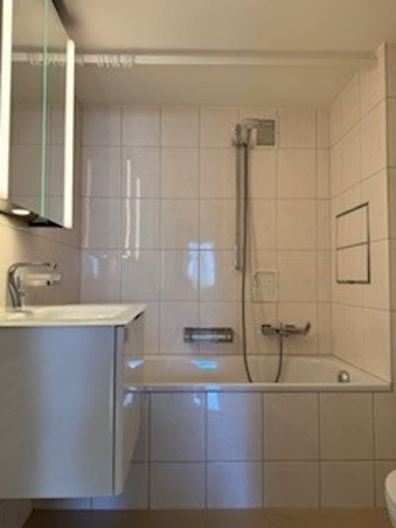 tiled bathroom, bathtub, white sink, mirror, shower