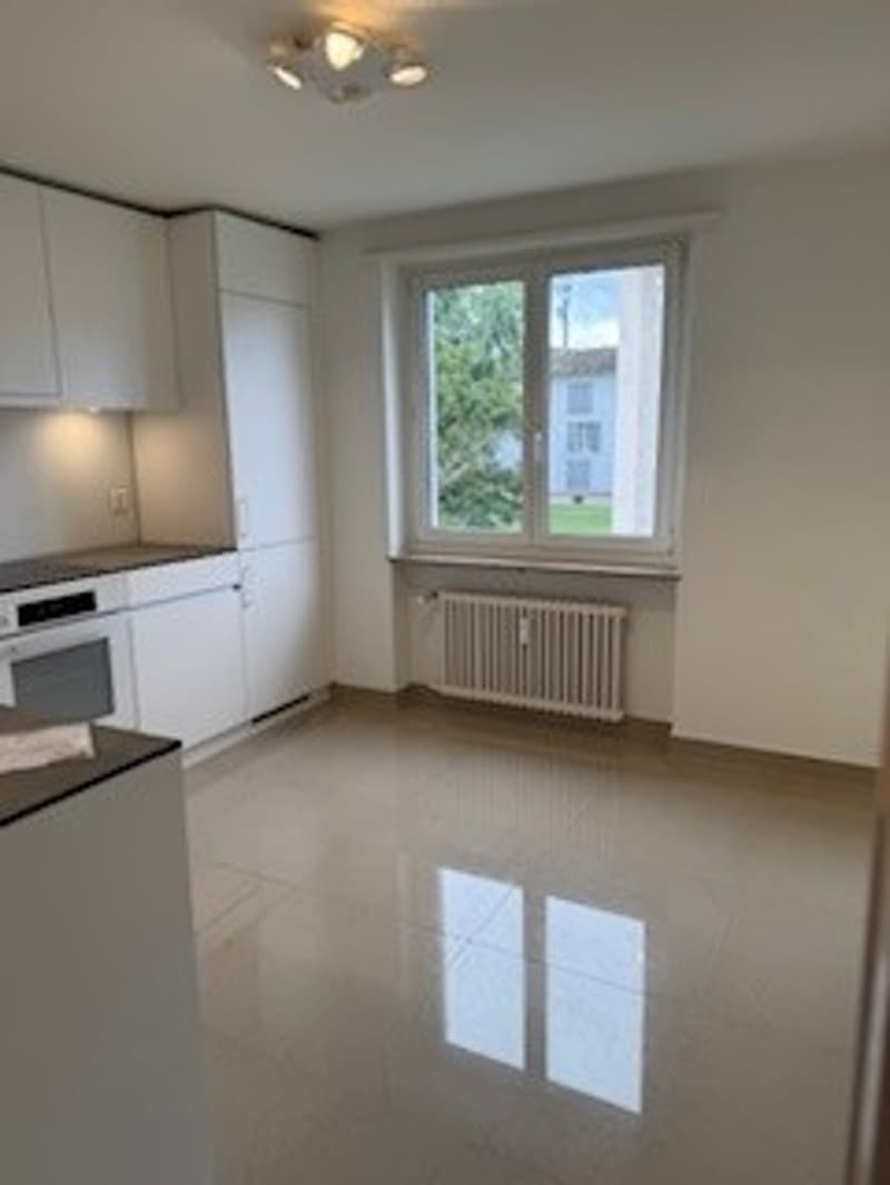 Empty kitchen with white cabinets, tiled floor, white ceiling, natural light