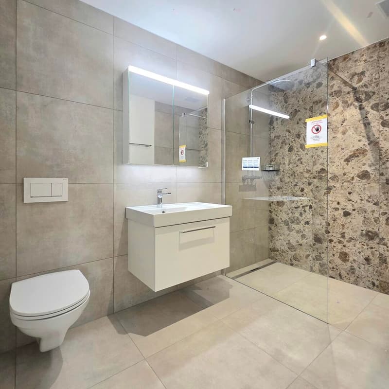 grosszügige Nasszelle mit Terrazzo- und Betonoptikplatten