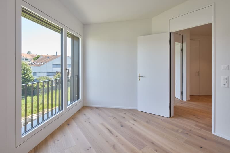 Empty room with white walls, balcony with railings, and large windows