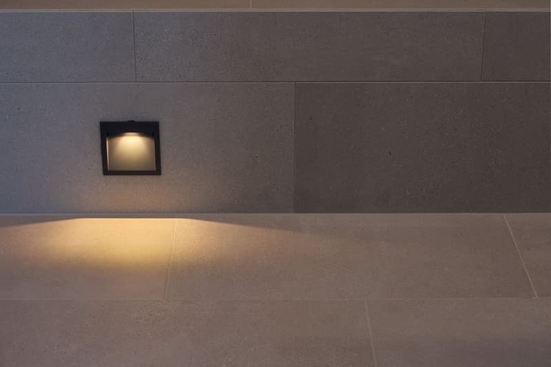 Concrete wall with integrated light, shadow on the floor, beige floor tiles