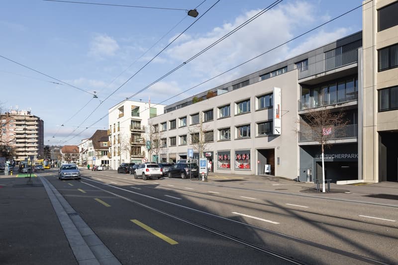 Street with tram and road, several cars parked in front of a building