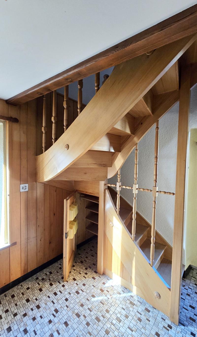 Interior with wooden staircase, tiled floor, wooden walls, storage under stairs