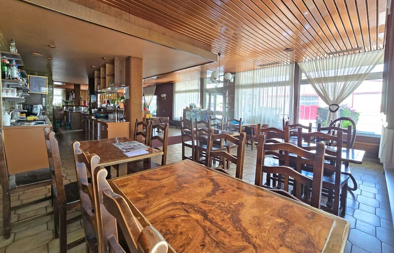 wooden chairs and tables, wooden ceiling, tiles, large windows, counter with shelves, coffee machine