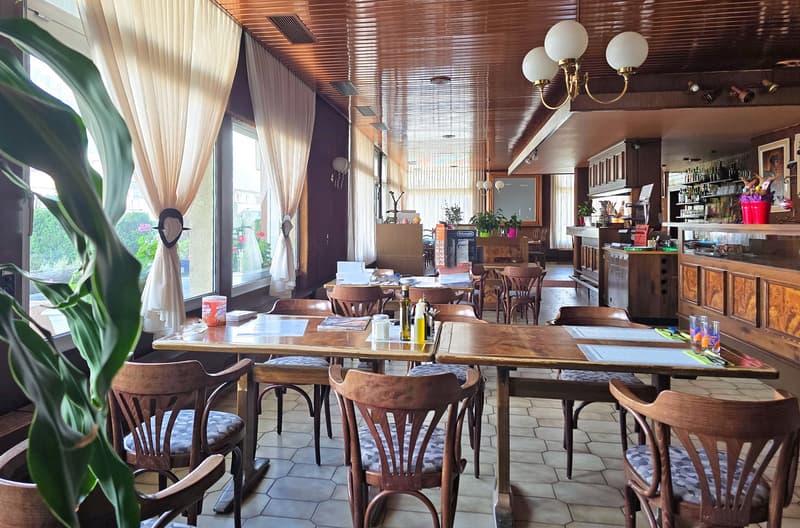 tables, chairs, glass windows, lamps, white tiled floor, potted plants, counter with bottles