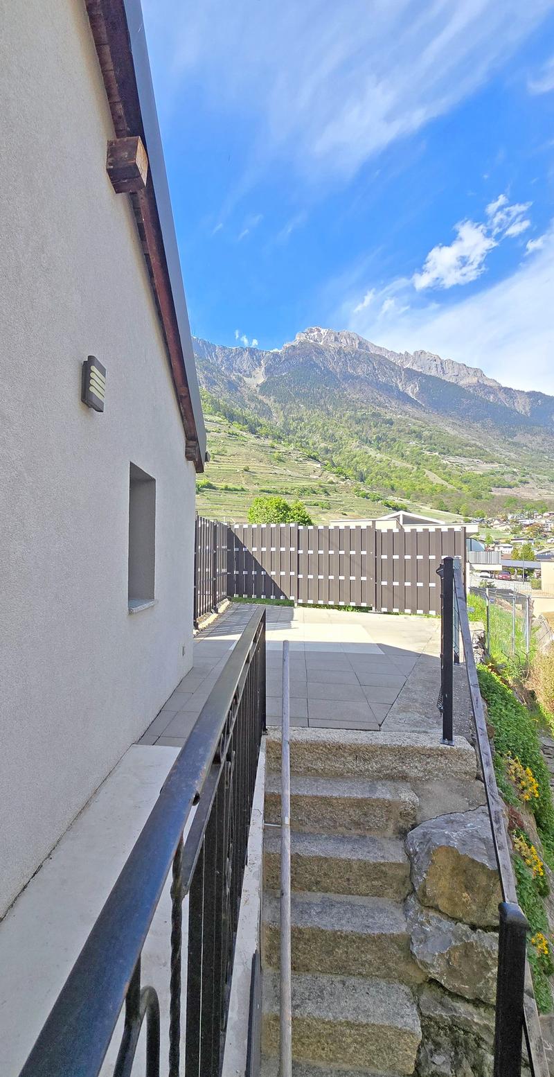 House with stone steps leading to the entrance, wall-mounted light, wooden fence, mountain view