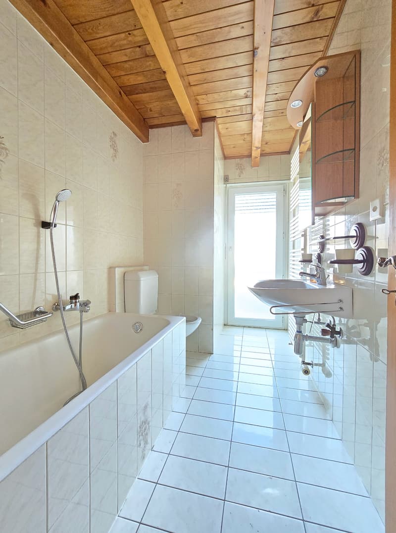 Bathroom with bathtub, toilet, sink, wooden ceiling, white tiles, shower head