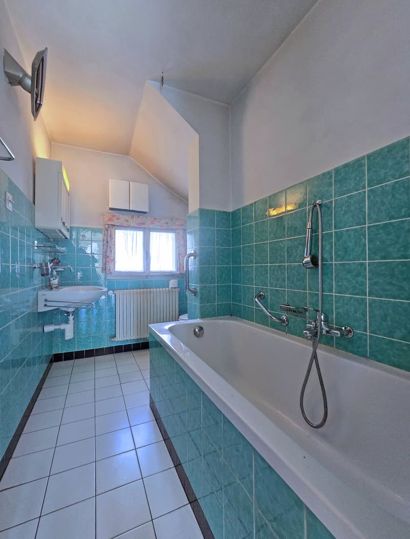 Bathroom with white tiles, turquoise tiles, bathtub, sink, radiator, window with curtains