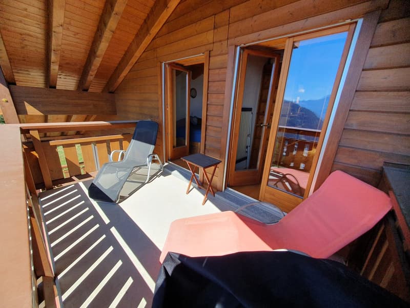 wooden deck, metal railing, wooden floor, lounge chairs, small side table, double doors leading to bedroom, large windows with views