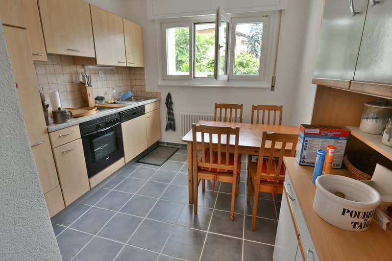 Spacious kitchen with wooden cabinets, tiled floor, oven, and dining table with chairs