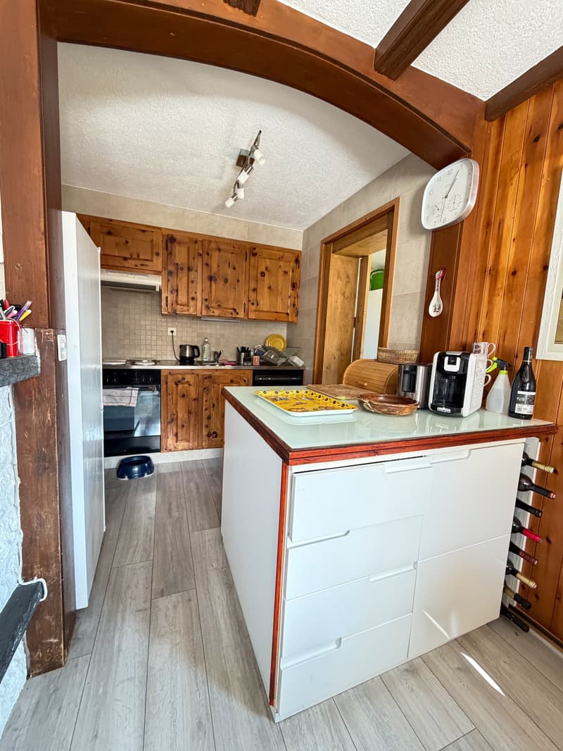 kitchen with wooden cabinets, white countertops, white drawers, wine bottles, coffee machine, clock, and a black oven