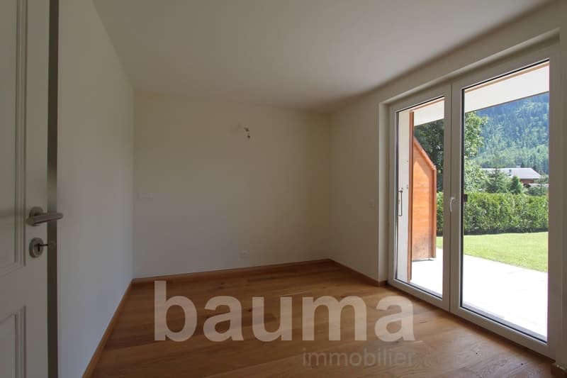 Spacious room with hardwood flooring, large windows providing a scenic view of the surrounding greenery and landscape.