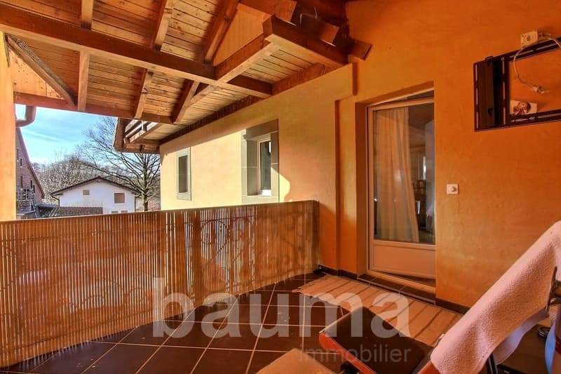 Outdoor terrace, wooden railing, tiled floor, door to room, glass door, hanging towel, sunny