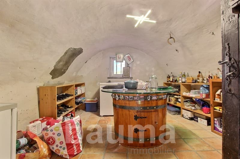Barn-style interior, wine bottles on shelves, open barrels table, kitchen appliances, framed photos on wall, horseshoe decoration