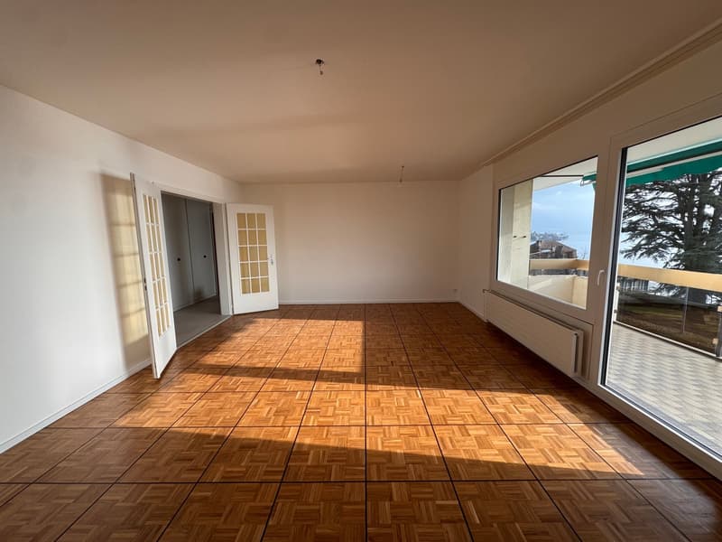 large room, wooden floor, large windows leading to a balcony, white walls, modern design