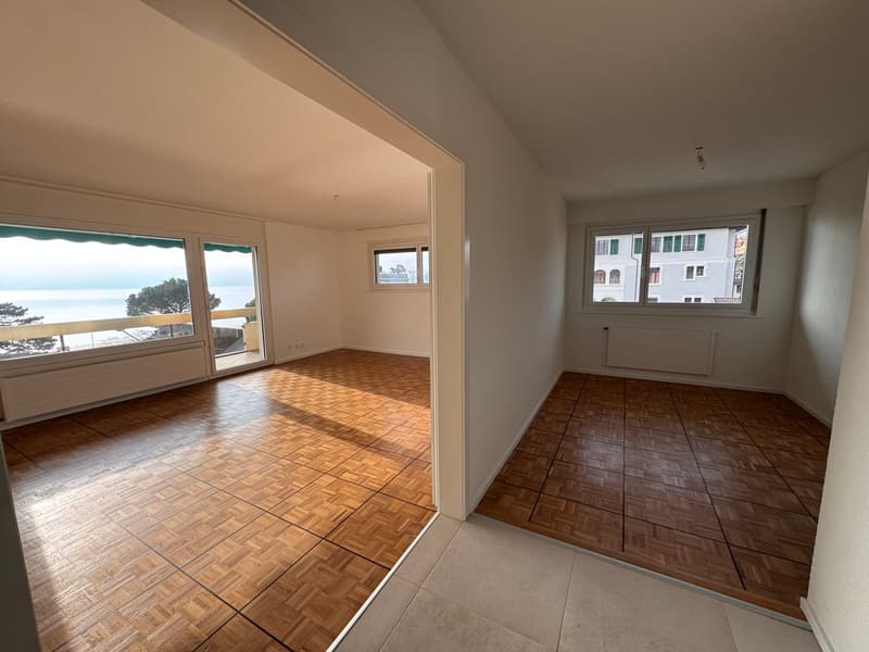 spacious room with wooden parquet flooring, large windows, white walls, sea view