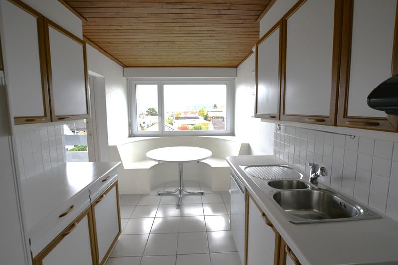 modern kitchen, white cabinets, tile flooring, round table, curved window seat, double sink, stainless steel appliances