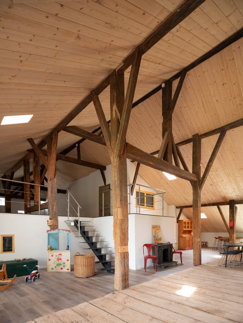 wooden beams, wooden flooring, red chairs, cabinet, fireplace, white walls, skylights