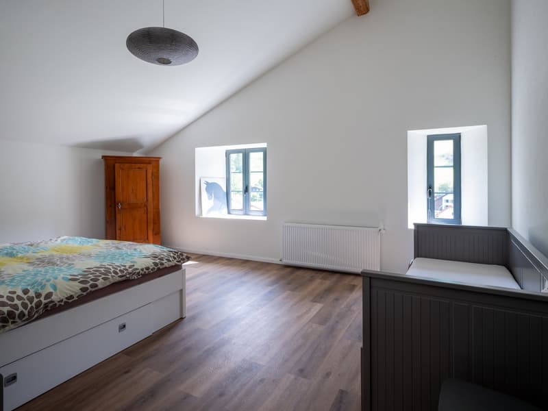 modern bedroom with wooden floor, bed, wardrobe, white walls, two small windows, white radiator, wooden beam