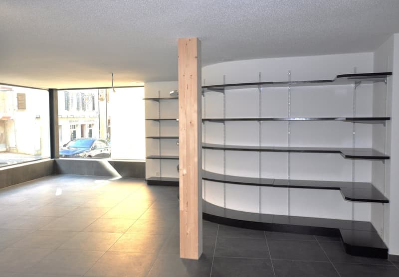 empty room with large windows, tiled floor, curvy shelves on the wall, wooden column in the center