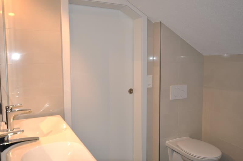 modern bathroom with sink, toilet, white tiled walls and floors, silver faucet