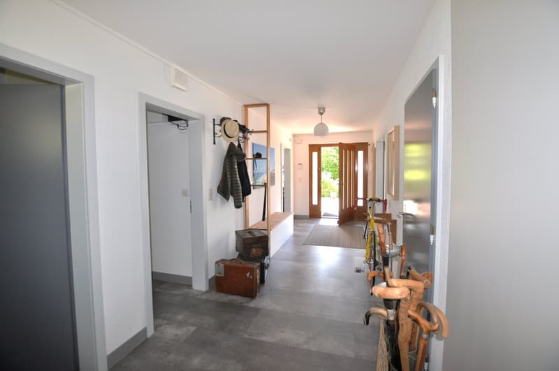 white walls, gray floor, coat rack, open doors, bicycle, umbrellas