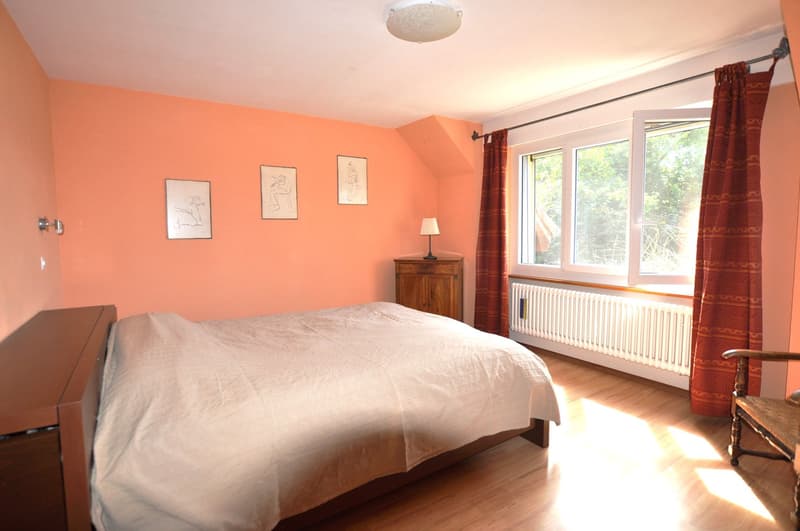 Double bed, wooden headboard, nightstand with lamp, radiator, paintings, curtain, wooden chair, wooden floors, lamps