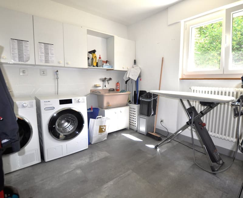 laundry room, two washing machines, ironing board, radiator, windows, shelves, cleaning supplies