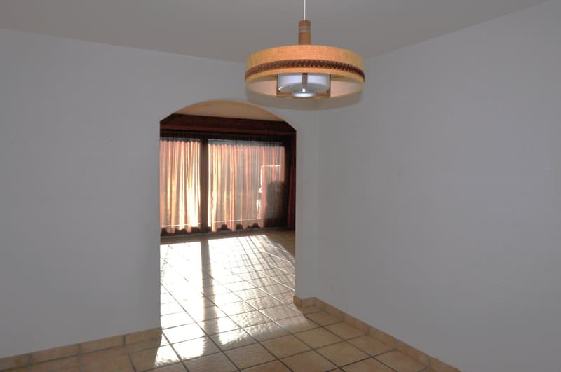 Empty room with white walls, wooden tiled floor, window with curtains, ceiling lamp