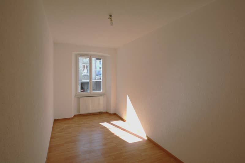 Empty room with white walls, wooden floor, white radiator, window