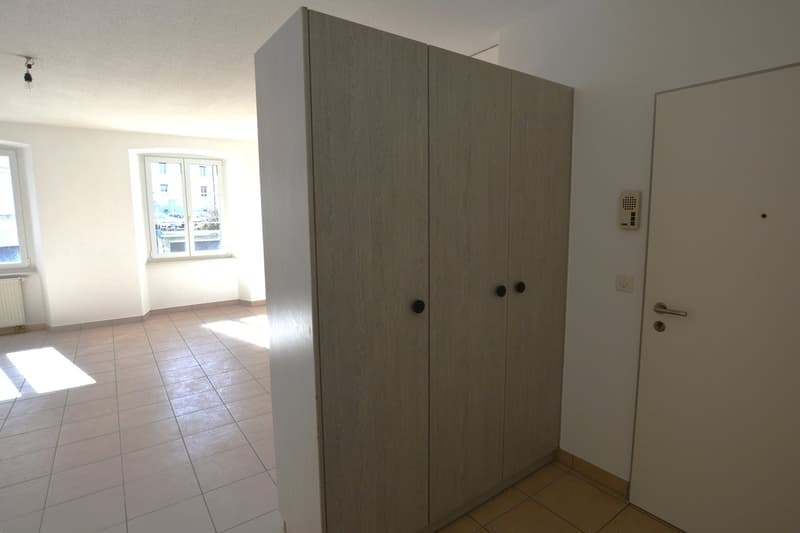 room, a closet with two doors, a radiator on the wall, a door on the right, and a window on the left wall