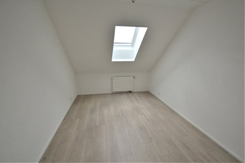 empty room with wooden floor, white walls, a skylight, and a radiator