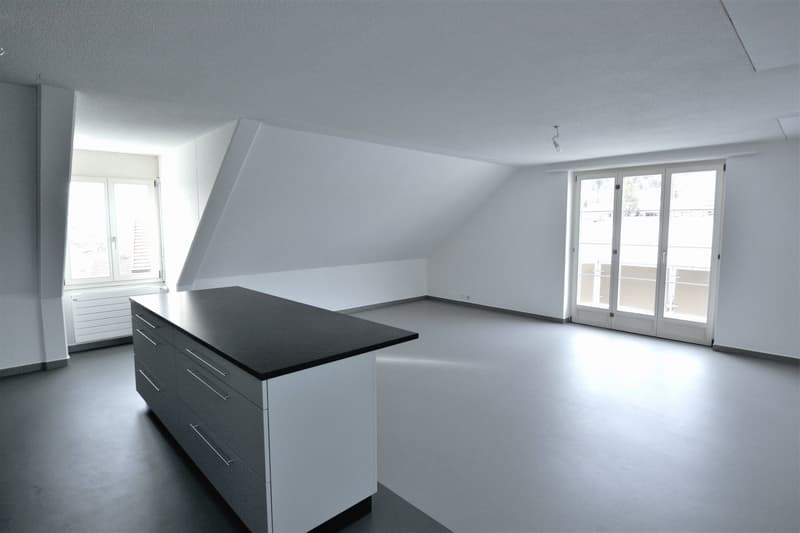 kitchen island with dark countertop, white cabinets, window with outside view, entrance door, sloped ceiling