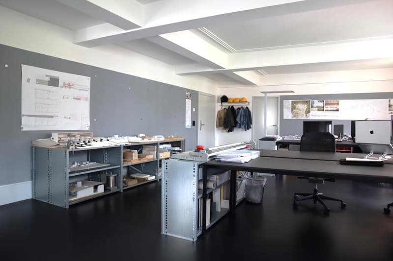 A large room with shelves, a desk, a chair, and papers.