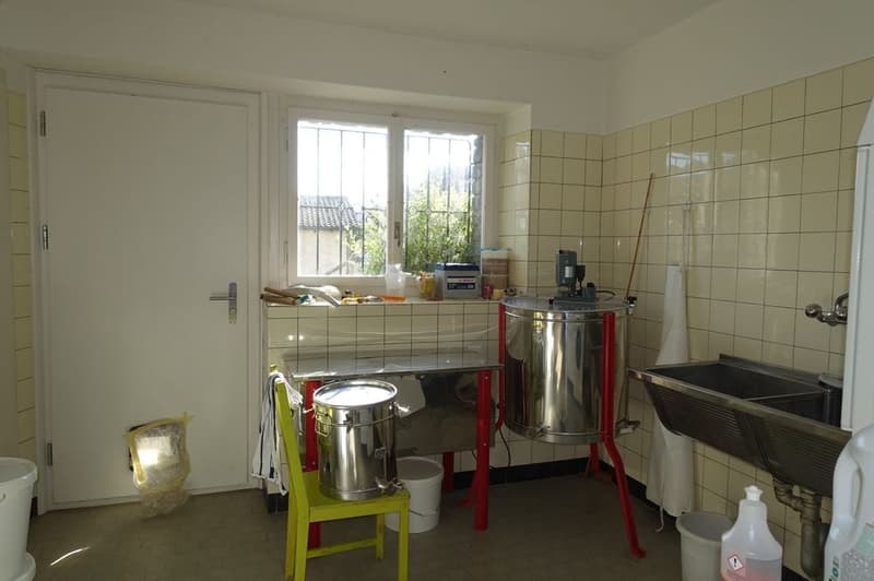 room with white tile walls, door, window, buckets, metal containers, stainless steel sink