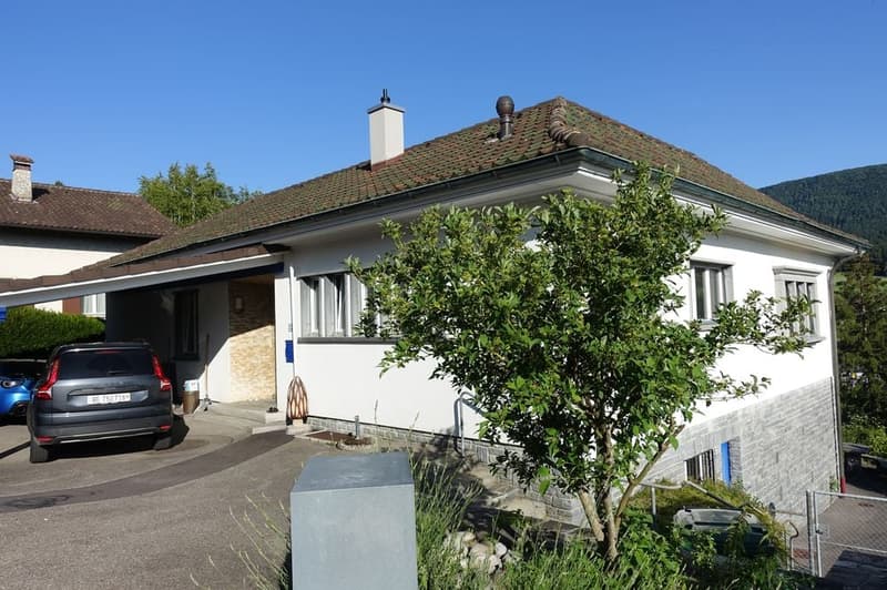 A house with white walls, brown roof, garage, chimneys, windows, and car parked in the driveway.
