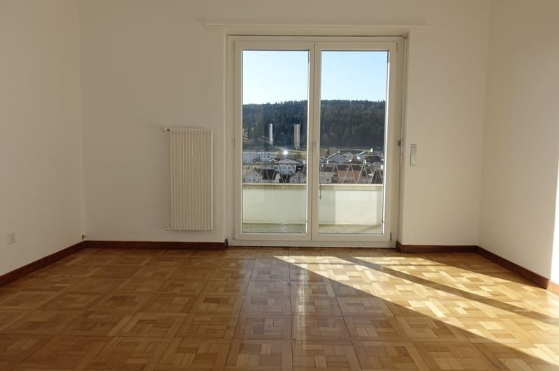 empty room with wooden parquet flooring, sliding glass doors leading to balcony, white walls and ceiling, and window view of mountains