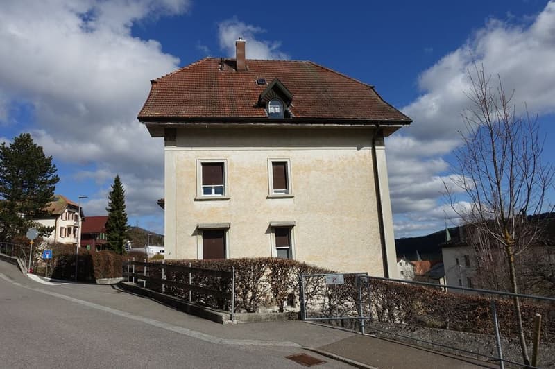 2 story house, brown roof, white exterior, raised ground floor, small garden