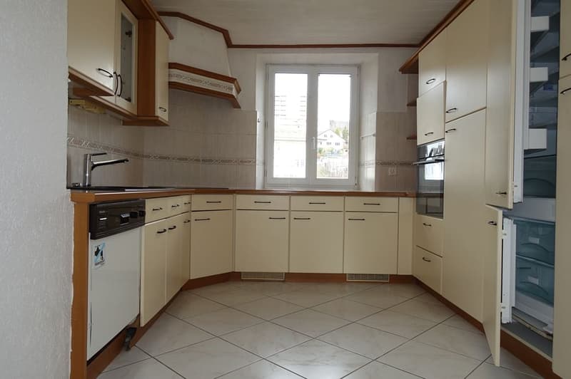 modern kitchen with white tiles, wooden cabinets, stainless steel sink, dishwasher, washing machine, window
