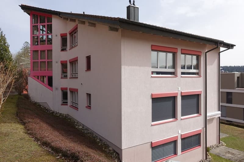 Modern apartment building with multiple windows, red trims, and a chimney on top