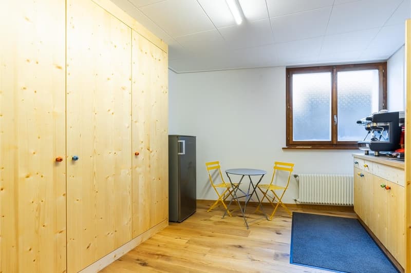 wooden cabinets, wooden floor, tall cabinets, refrigerator, yellow chairs, round table, radiator, window, coffee machine