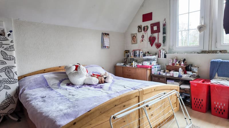 bedroom with a bed, wooden cabinet, shelf with personal items, two red laundry baskets, white clothing rack