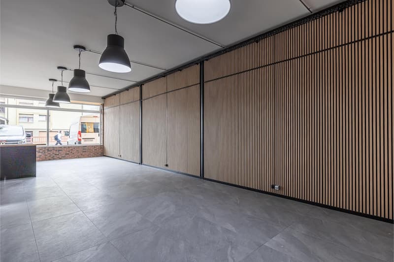 Empty room with gray tiled floor, wooden wall panels, and hanging lamps