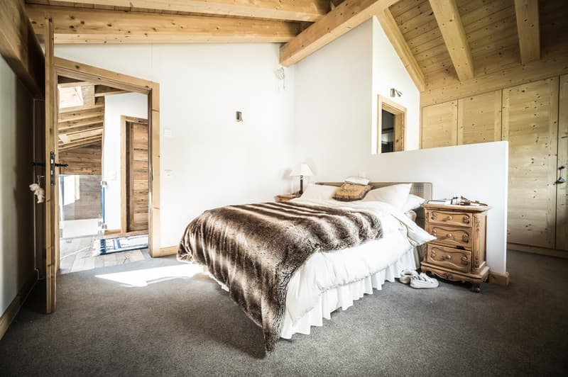 Master bedroom with wooden ceiling, carpeted floor, bed, nightstand, and lamp