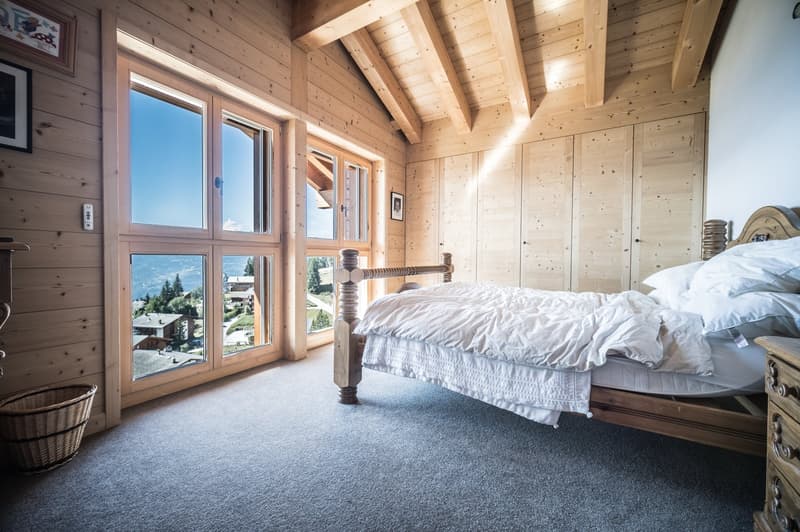 ample daylight from large windows, wooden wall, cozy wooden bed, woven basket, wooden chest