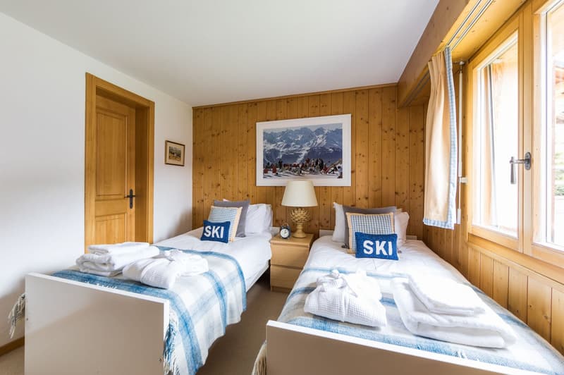 Wooden walls, 2 twin beds, nightstands with lamps, and picture frames