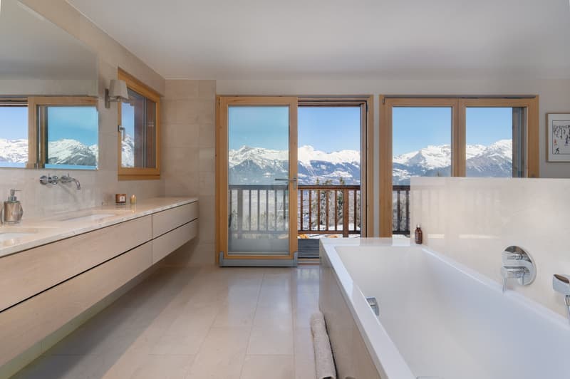 Marble tiles, wooden vanity, bathtub, double sinks, large mirror, large sliding glass doors with balcony, stunning mountain view