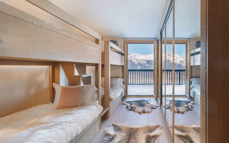 4 bunk beds, white fur bedding, carpeted floor, view of snowy mountains